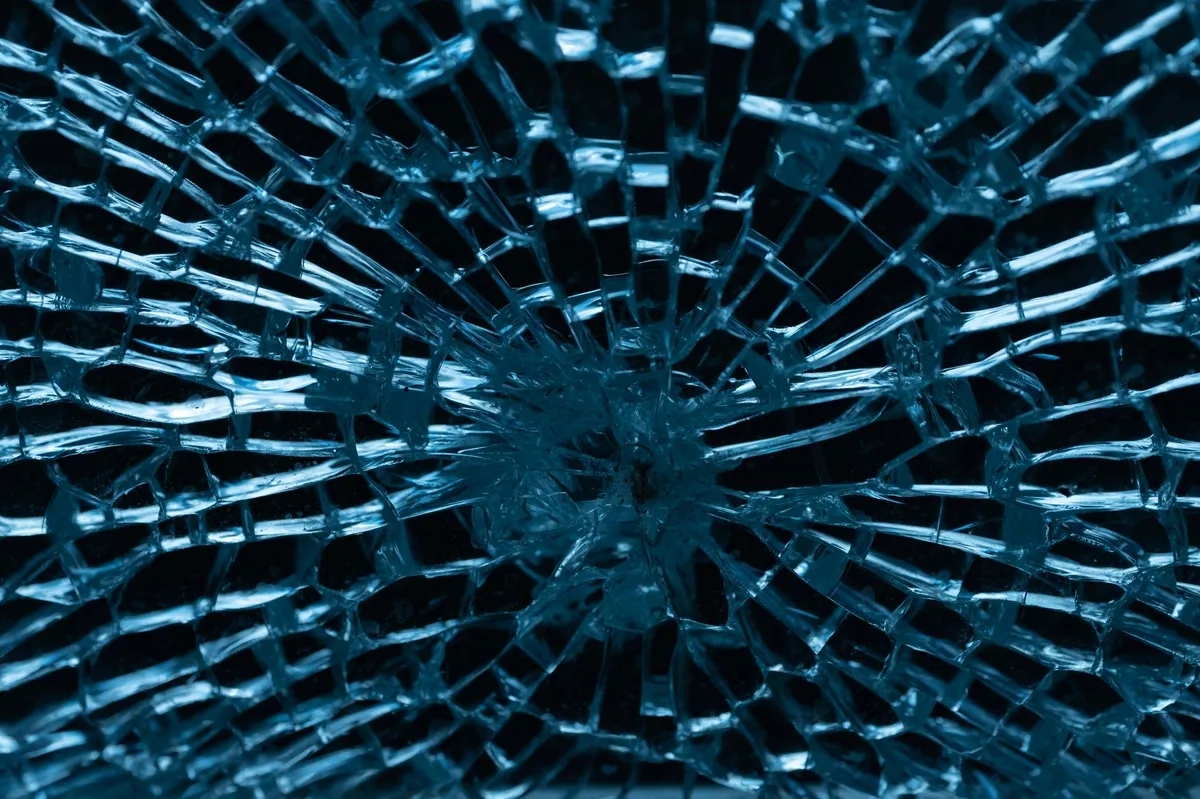 broken glass of a windshield, the fractures pointing to the center where the point of impact is