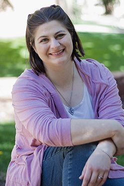 Mandy Tremelling, author, smiling at the camera wearing a pink and white top and blue jeans